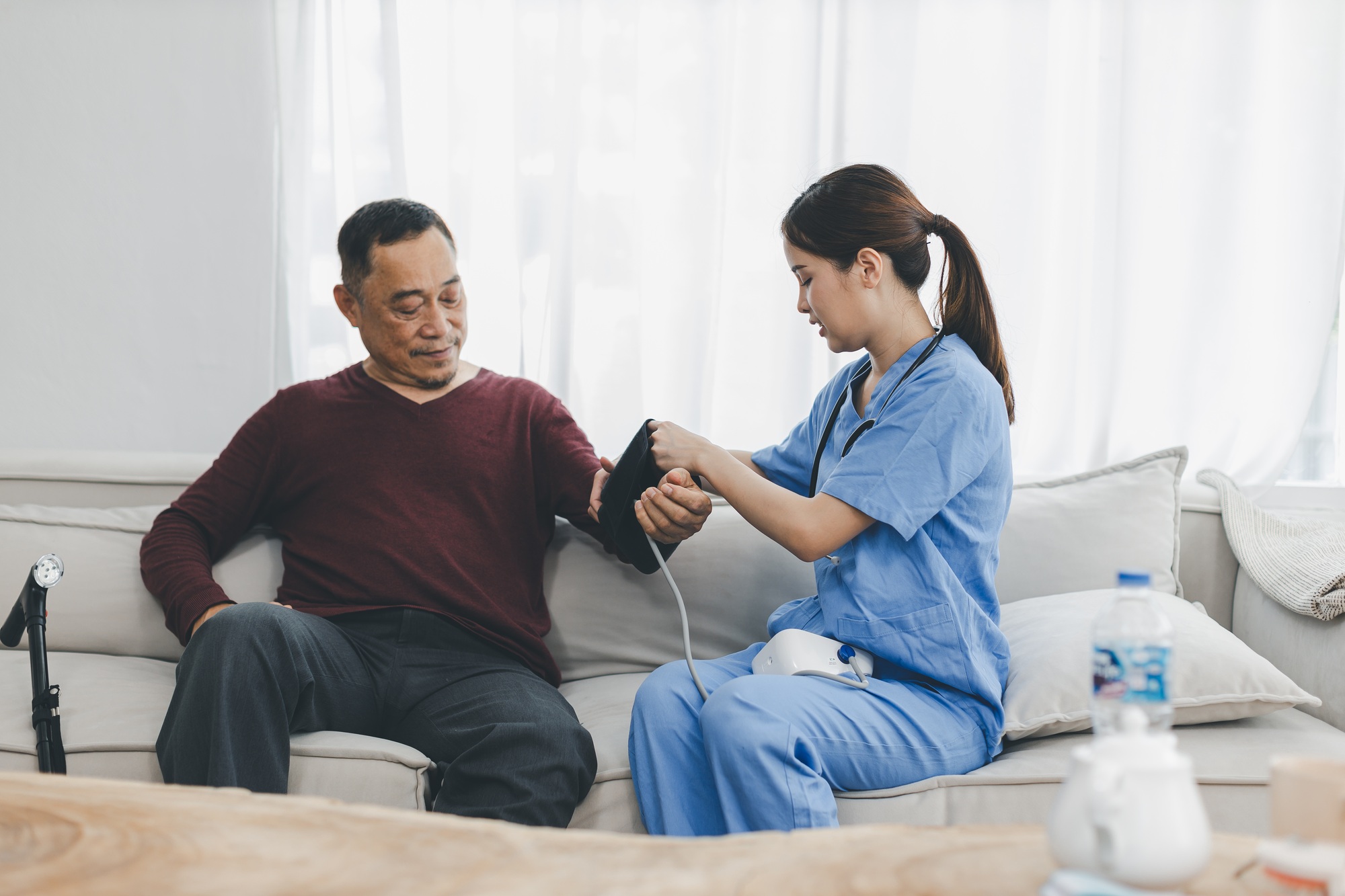 Caregiver nurse measuring blood pressure by using digital sphygmomanometer Senior patient at home