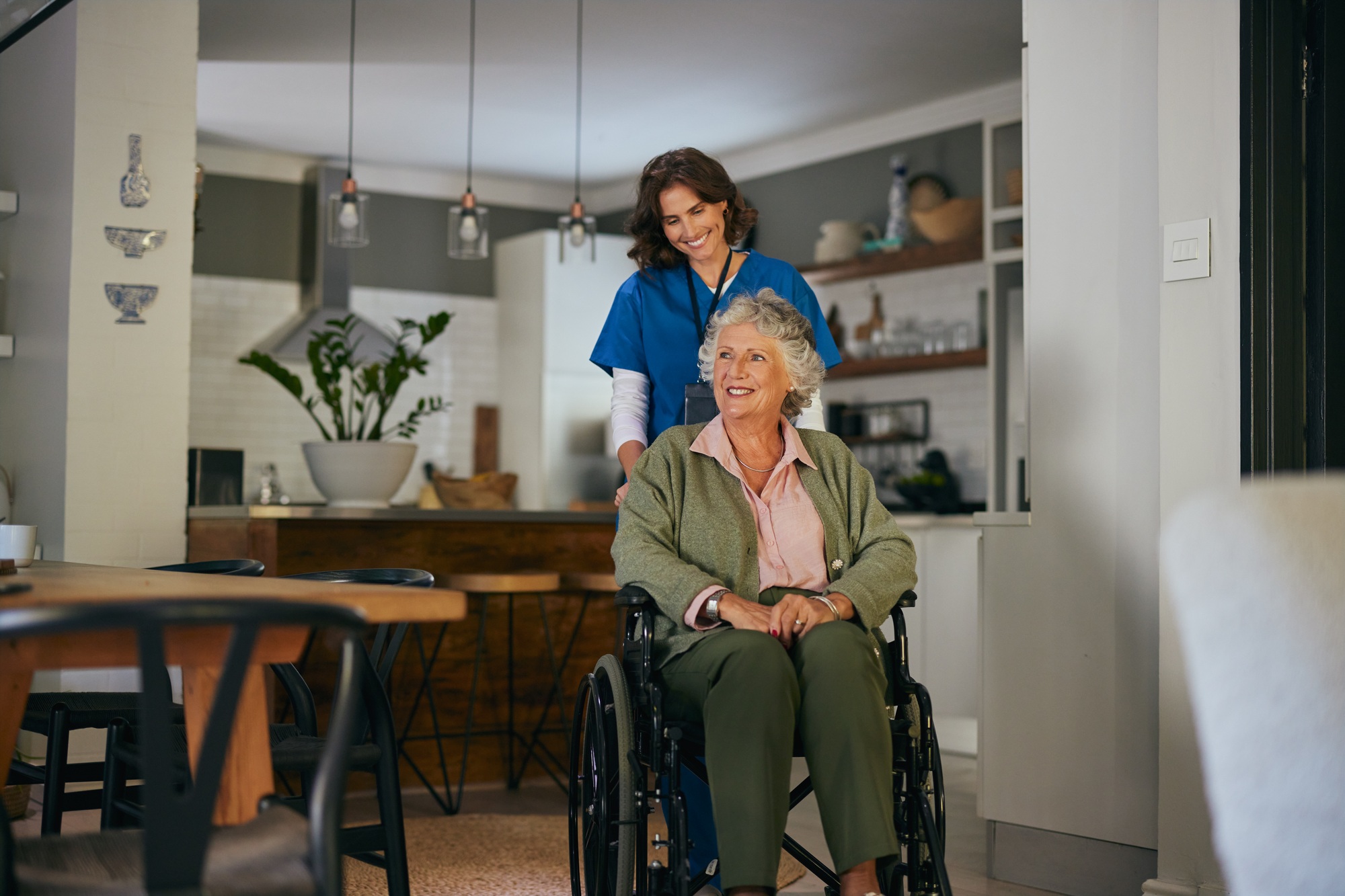 Nurse pushing disabled senior woman on wheelchair at home