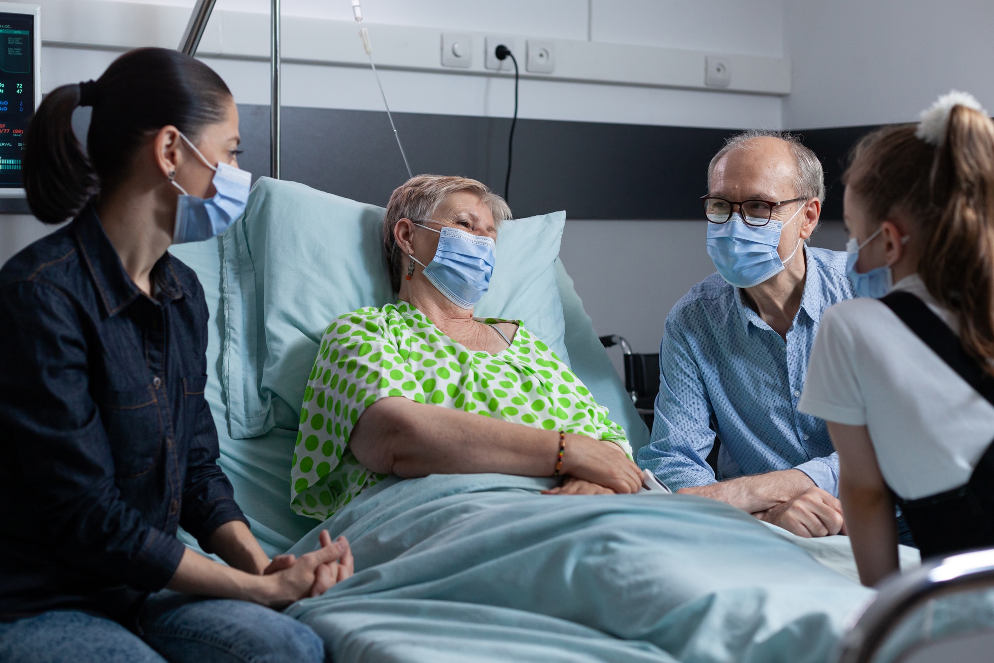 Senior female in bed receiving visitors at medical clinic